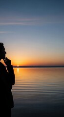 Fototapeta premium Silhouette of a reflective individual, contemplating the profound essence of life at a tranquil sunset over calm boundless water, envisioning a hopeful tomorrow.