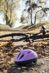 Naklejka premium Purple helmet lies abandoned on the pavement beside a toppled bicycle, evidence of a sudden fall.