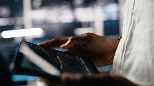 Close up of data center programmer using tablet, writing code for resource optimization, performing updates. Server room employee using device, compiling software patches to fix bugs, camera A