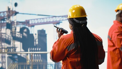 Offshore platform specialist using portable radio device to monitor systems during operations. Drilling rig technician using walkie talkie, doing emergency procedures, calibrating equipment