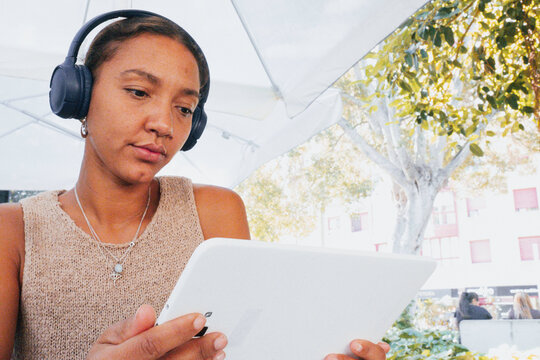 Young woman wearing headphones using digital tablet outdoors