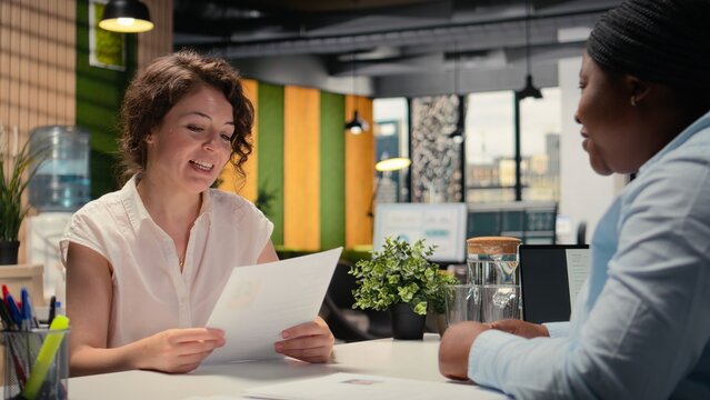 Hiring manager conducting a detailed job interview with applicant, reviewing the candidate qualifications, CV resume and potential onboarding for career advancement within the company. Camera A.