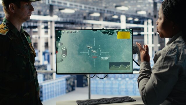 Military data center coworkers looking at radar software on screen to watch for enemy threats. Team of army employees in data center scans suspicious activity to detect dangers, camera B