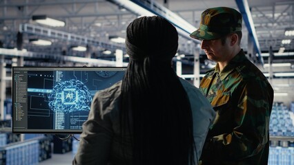Military staff in server room uses AI tools to help manage computer systems. Army team wearing...
