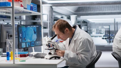 Male science expert operates with microscope and laboratory tray, studying chemical and biological samples for medical research. Magnified observation of DNA in modern science.