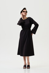 Fototapeta premium A pregnant model girl in stylish clothes poses on a white background.