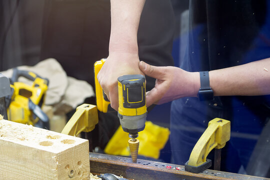 Craftsman using cordless screwdriver with step drill bit to drill metal
