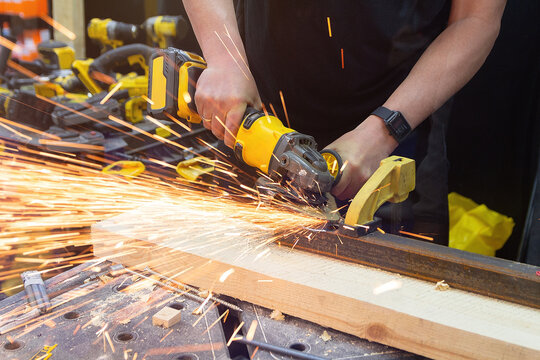 Craftsman using a grinder to cut metal in a workshop with sparks flying