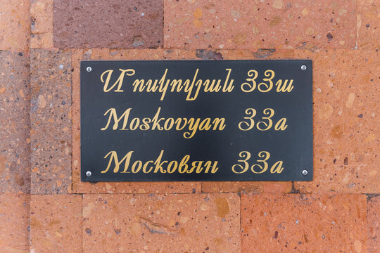 View of a black sign with gold lettering displaying the address in both Armenian and English, mounted on a textured brick wall, Yerevan, Yerevan, Armenia.