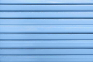 Close-up of blue metal wall with horizontal lines, showing smooth texture and glossy surface of...