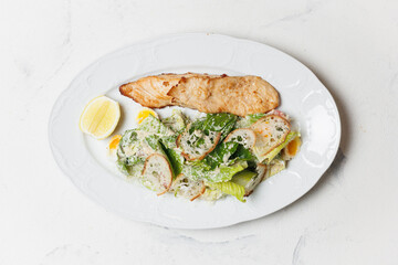 Grilled Salmon and Caesar Salad with Lemon on a White Plate