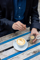 Man hands holding coffee cup and stirring sugar