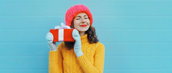 Christmas portrait of happy young woman smiling holding holiday gift box, cheerful girl celebration