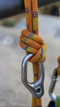 Orange Climbing Rope Tied With Bowline Knot to Metal Carabiner