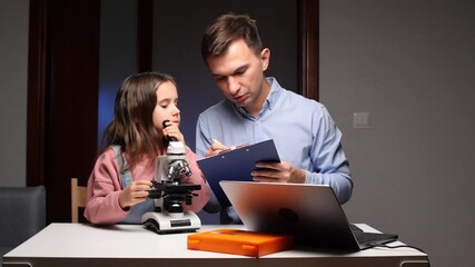 Father daughter learning science using microscope observing samples