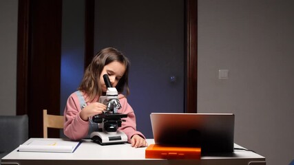 Little girl exploring microworld with microscope during science lesson - Powered by Adobe