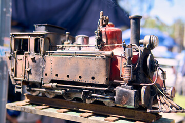 View of a colorful, well-maintained, handcrafted locomotive. For decoration or souvenirs. Made from recyclable materials. In a public place, with natural light.