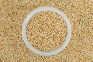 white quinoa seeds in ceramic bowl as a background. Top view. Flat lay
