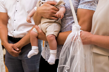 Parents hold their baby during a baptism ceremony, surrounded by loved ones, symbolizing faith, family, and the welcoming of the child into the Christian community.