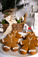 There are gingerbread men on the plate. A decorated Christmas tree and festive ornaments are in the background.