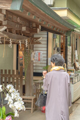 Fototapeta premium 小さな祠に手を合わせる女性の後ろ姿