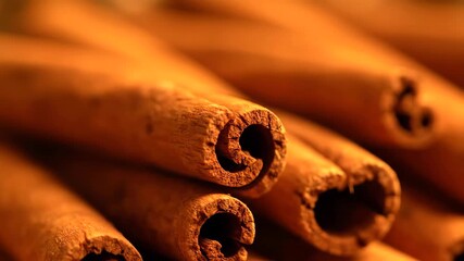 Extreme close-up of stacked cinnamon sticks with a slow slide camera movement under warm ambient light