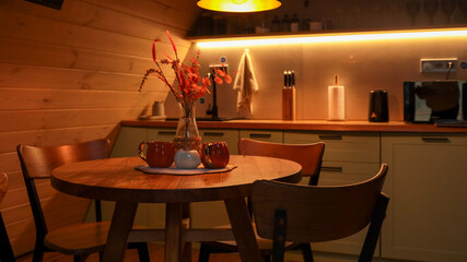 Cozy kitchen interior with wooden table, chairs, and warm lighting