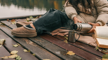 Enjoying a warm drink on a wooden dock by the lake in autumn