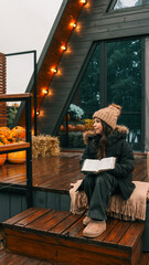 Young girl reading a book outdoors on a wooden deck in autumn