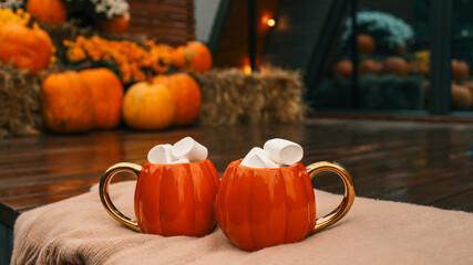 Cozy autumn scene with pumpkin mugs filled with marshmallows