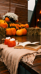 Cozy autumn scene with pumpkins, mugs of cocoa, and a book