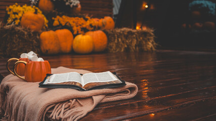 Cozy autumn scene with pumpkins, mugs, marshmallows, and an open book