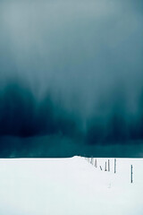 "Moody Winter Landscape with Fence and Stormy Sky"