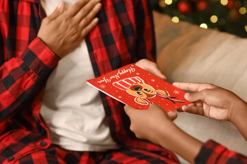 Teenage girl giving greeting card to her mother at home on Christmas eve, closeup