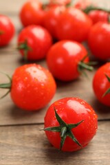 Wet ripe red tomatoes on wooden table, closeup