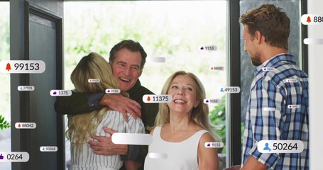 Greeting senior couple hugging adult daughter at doorway, with glass panels and notification icons