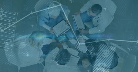 Five medical professionals reviewing patient data in hospital meeting with clipboards and tablet