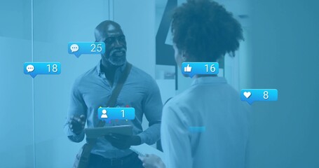 Colleagues reviewing social media metrics in office hallway with clipboard paper and floating icons