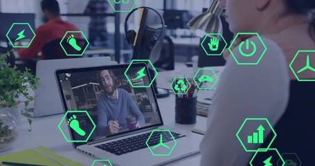 Checking laptop screen worker viewing colleague holding coffee in office meeting, with green icons