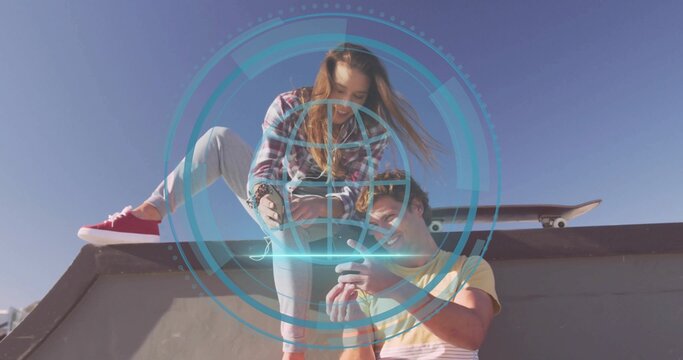 Leaning pair in skate gear checking phone on skatepark ramp with skateboard, holographic interface