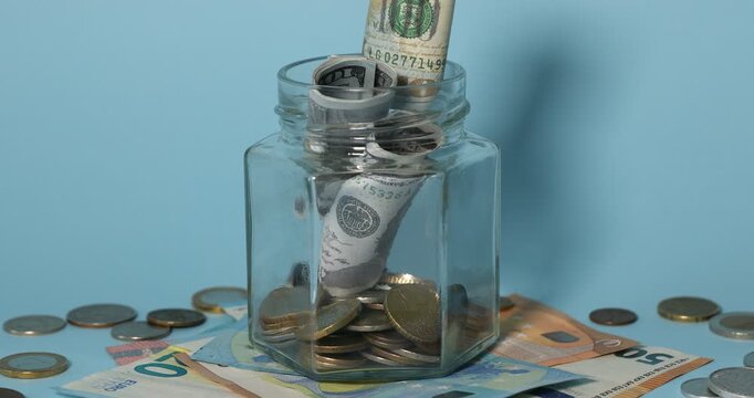 Dollar banknotes falling into jar on light blue background, closeup. Money savings