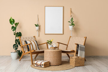 Interior of living room with armchairs, houseplants, suitcase, basket and books on wicker table near beige wall