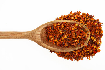Close-up of red chili powder in rustic wooden spoon on white background