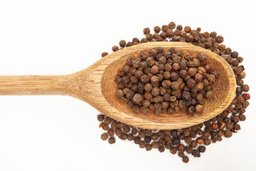 Detail of black peppercorns in wooden spoon on white background