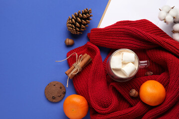 Winter composition with cup of cocoa, mandarins and sweater on blue background
