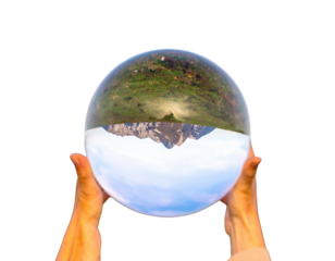 Hands Holding a Crystal Ball Reflecting a Mountain Landscape.
