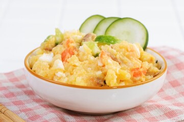 Close-up of creamy Japanese potato salad in a ceramic bowl topped with cucumber garnish. Simple Asian comfort food suitable for ads, menu design, or editorial food concept.