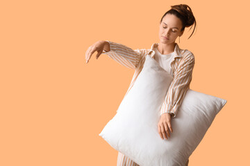 Female sleepwalker in pajamas with pillow on beige background