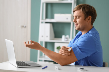 Male doctor with glucose sensor giving online consultation in clinic