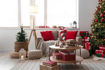Interior of living room with Christmas tree, sofa and books on table